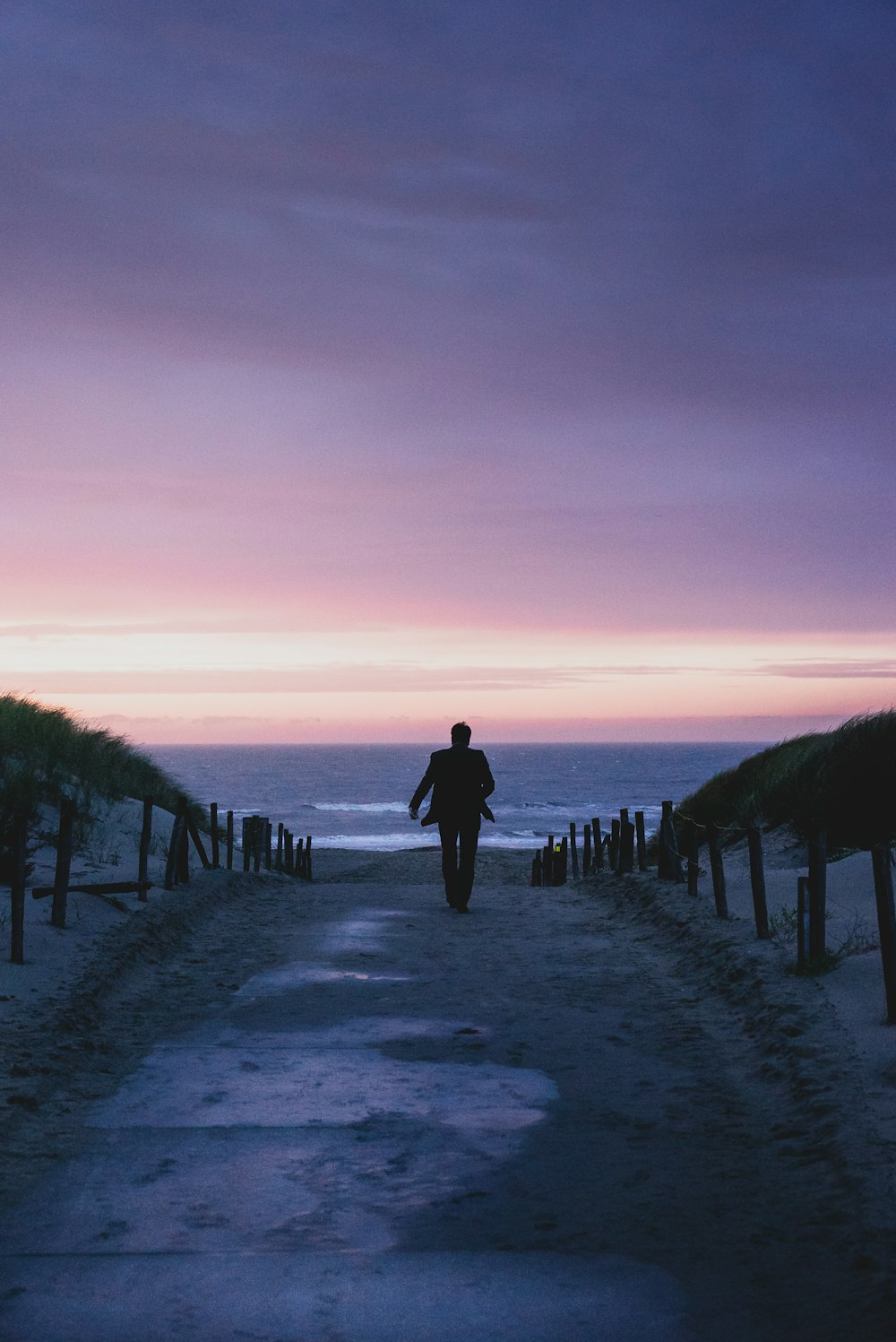 Silhouette eines Mannes, der während der goldenen Stunde vor dem Meer spazieren geht