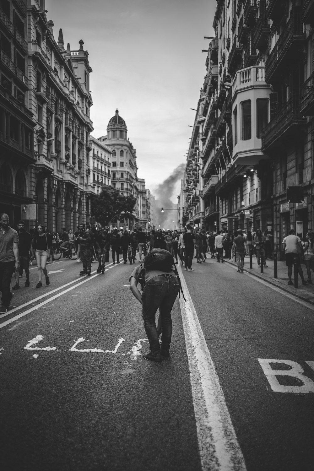 Fotografía en escala de grises de personas caminando por la carretera junto a los edificios