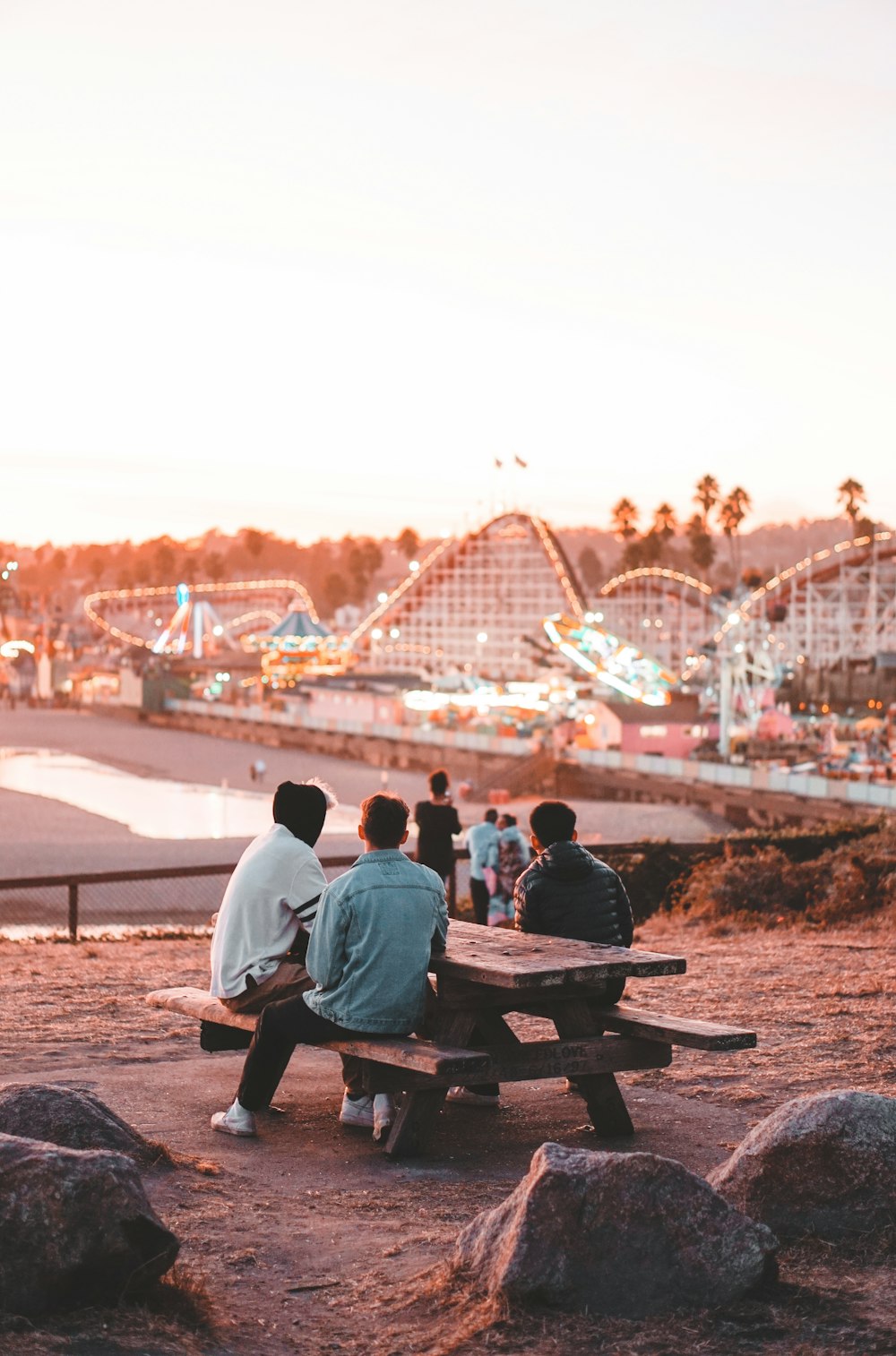 three men sitting on picnic table near circus