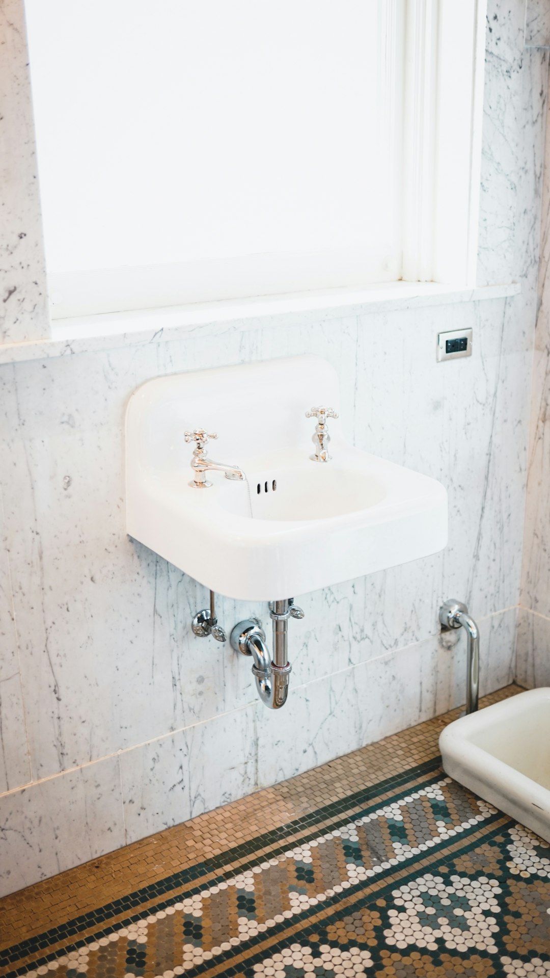 two faucet on sink near window