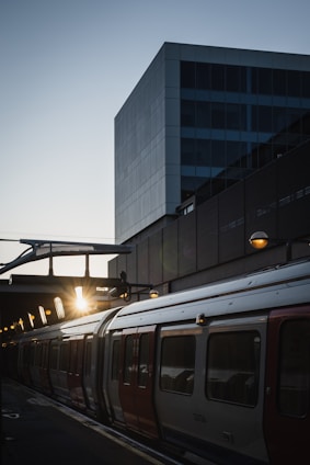 A sleek metro train arriving at a bustling city station during sunset.