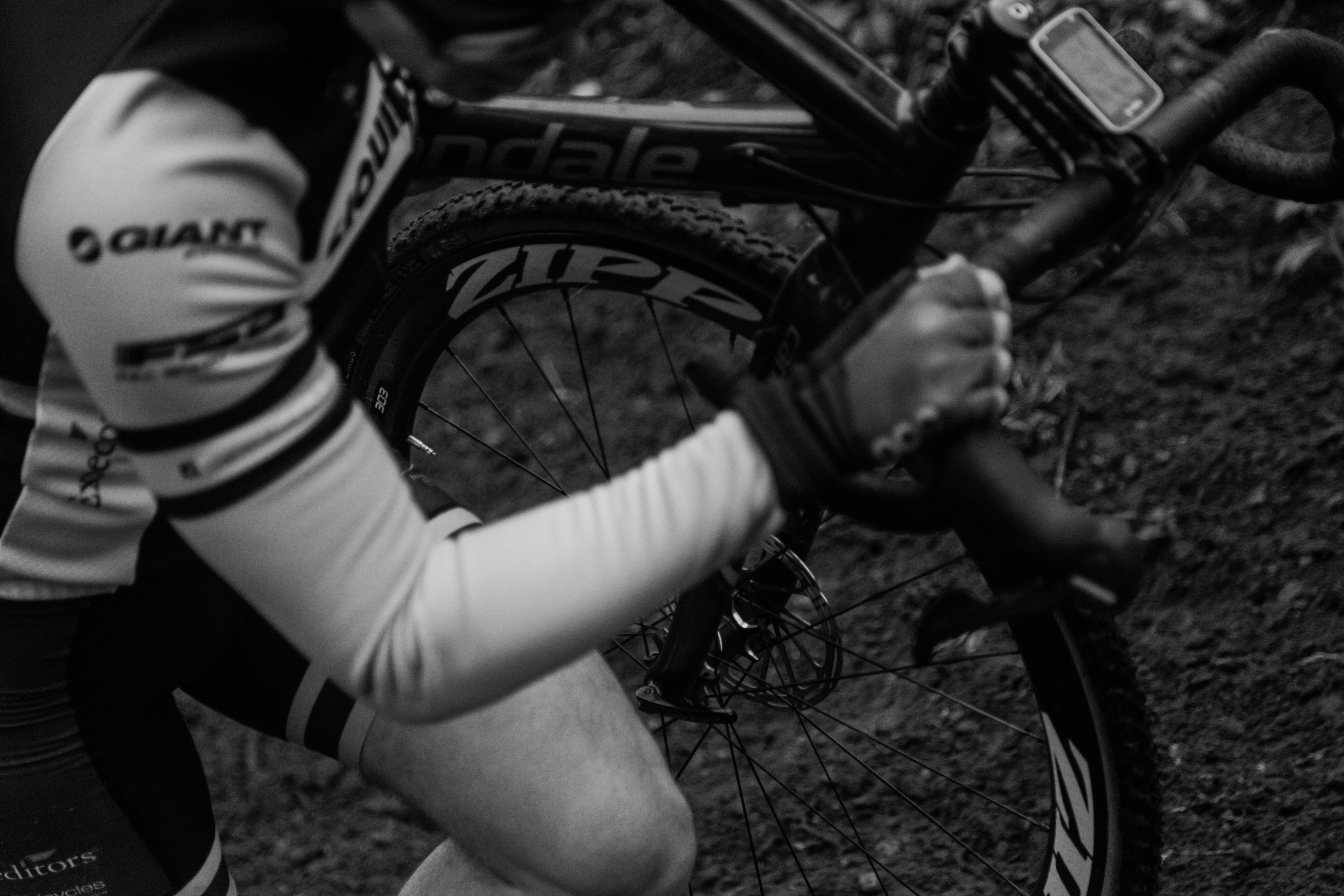 grayscale photography of man holding bike