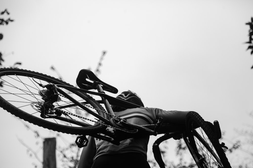 greyscale photography of man carrying bike