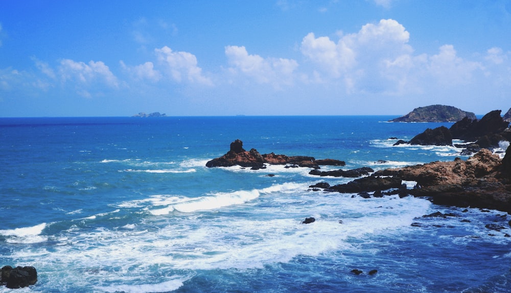 sea waves crashing on rocky shore during daytime