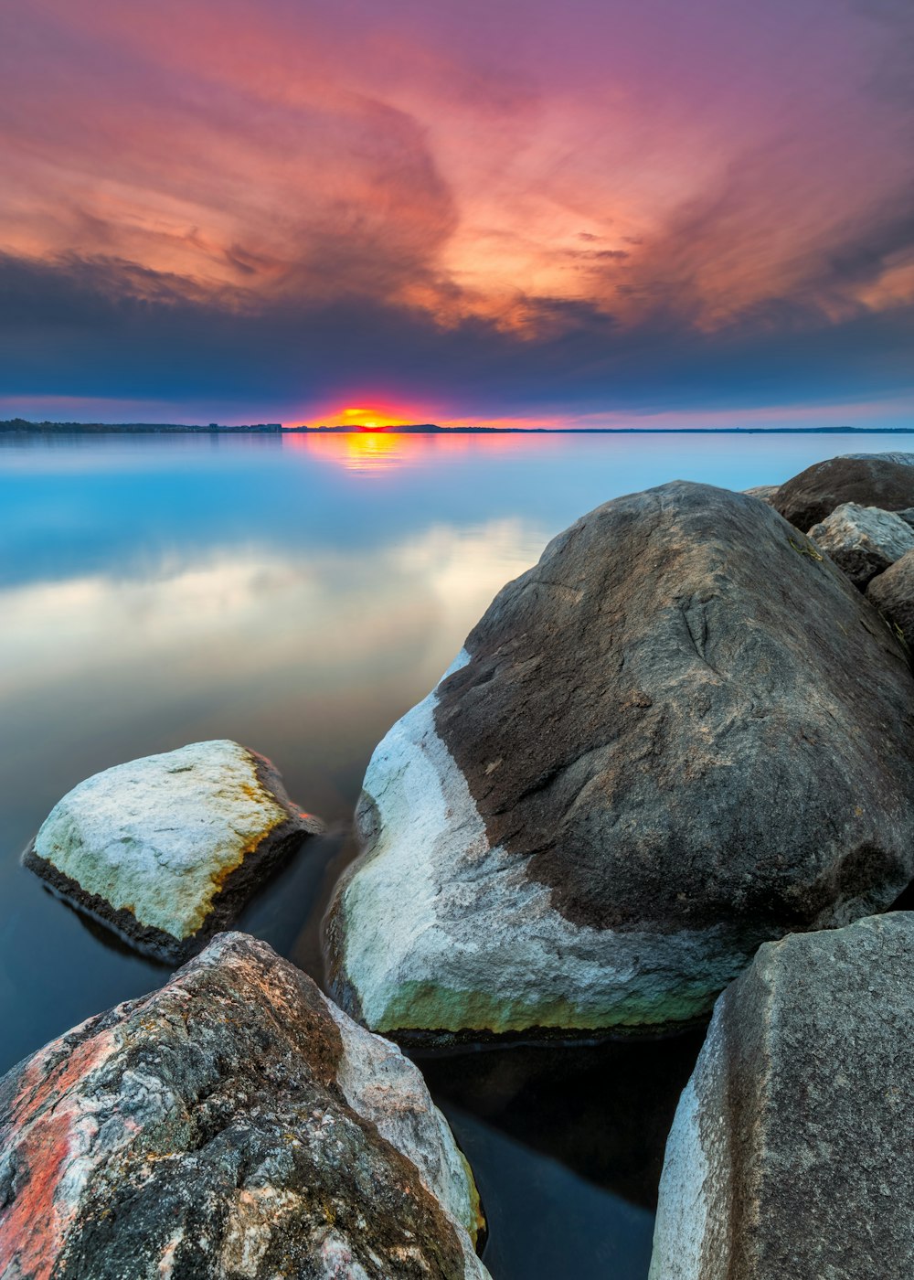 brown rock on body of water during sunset