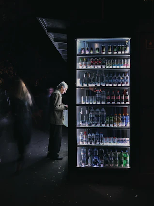 A friendly Vendease technician restocking a vending machine inside a bright office lobby.