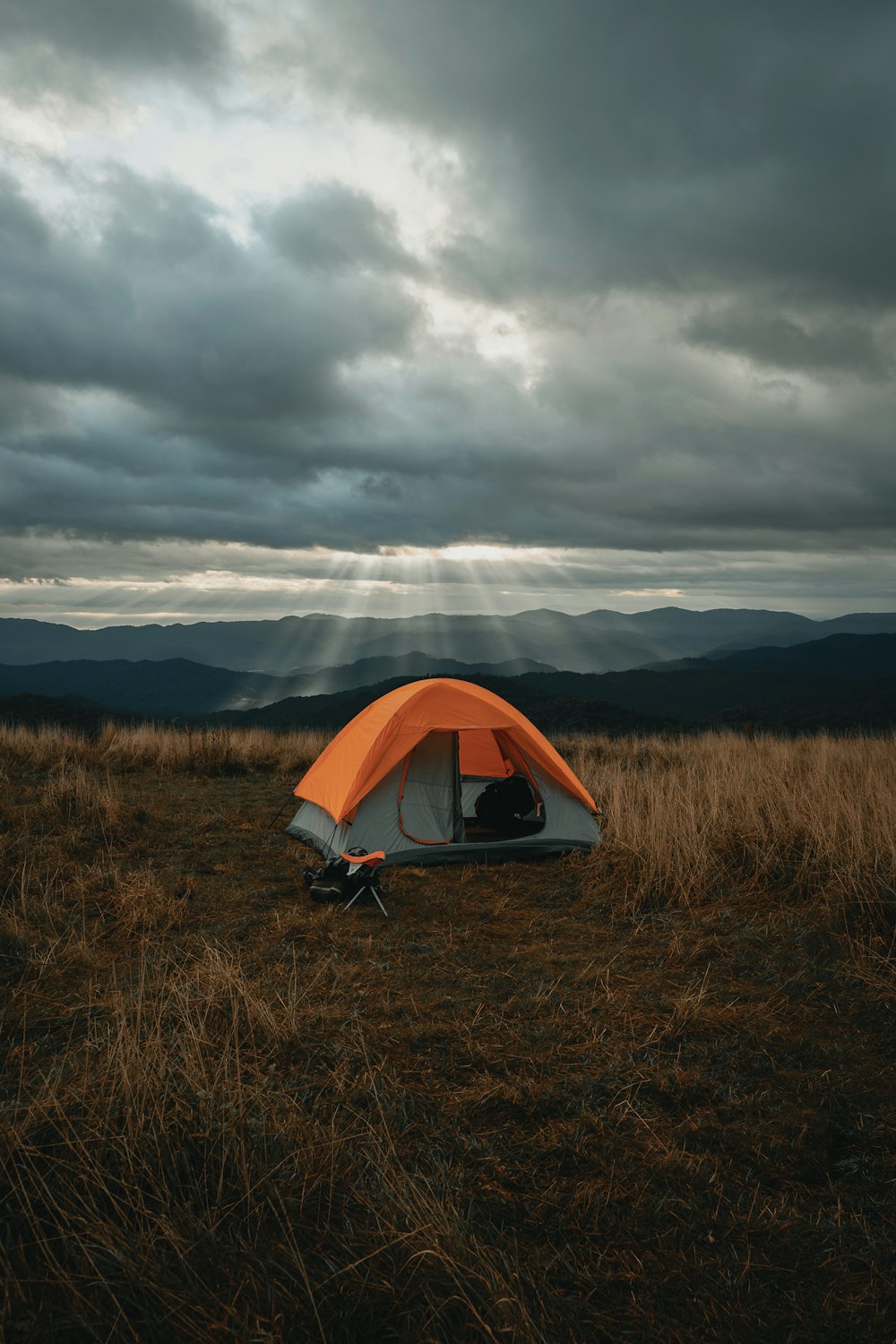 set-up gray and orange tent on brown field under cloudy sky