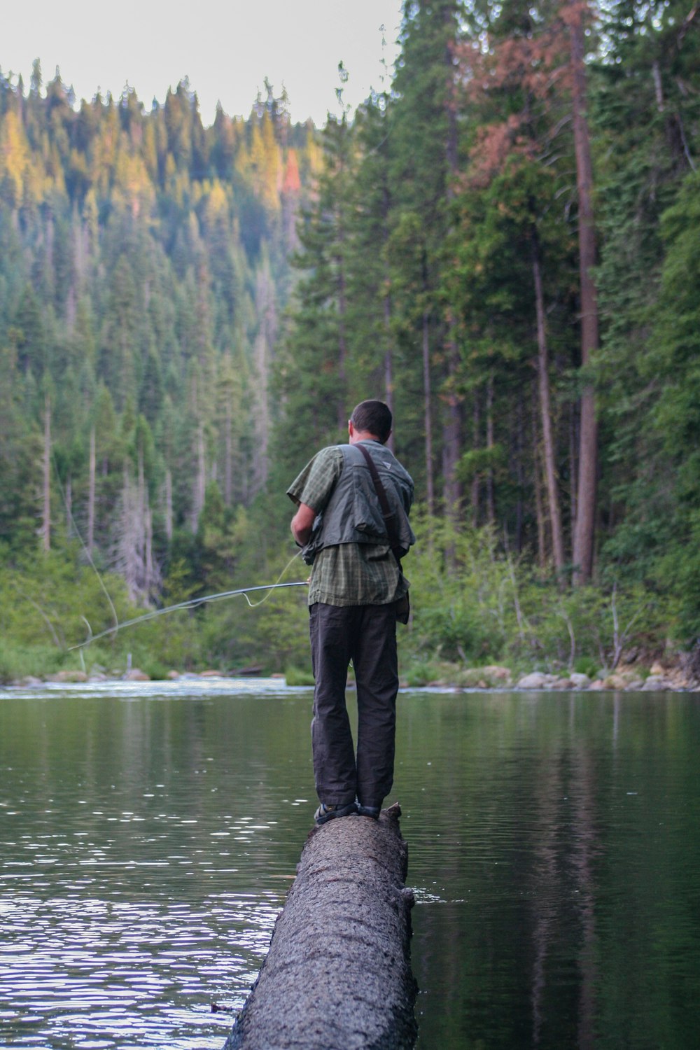 man wearing grey shirt and black pants standing on log