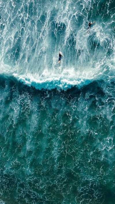 two surfers riding a large wave in the ocean