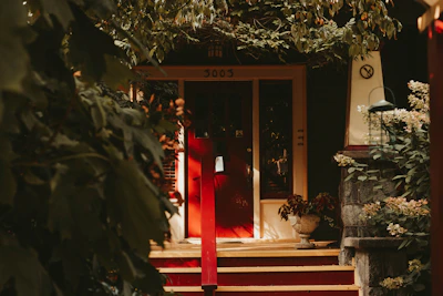Circular image of a cozy villa entrance with bold red door accents and subtle shadowing.
