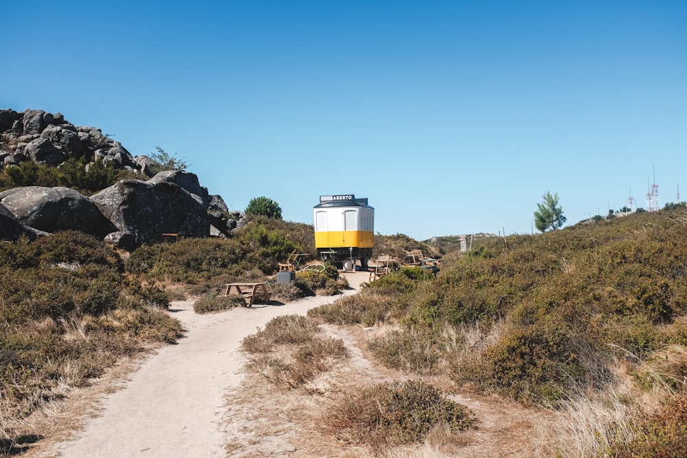 a yellow and white truck parked on a dirt road