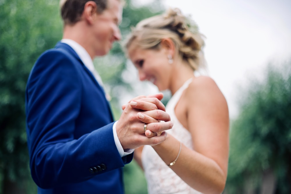 woman in white gown dancing with man in blue suit jacket