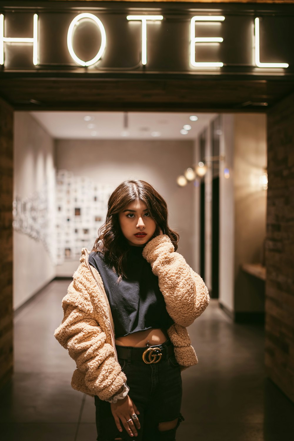 woman standing in front of Hotel neon signage turned on