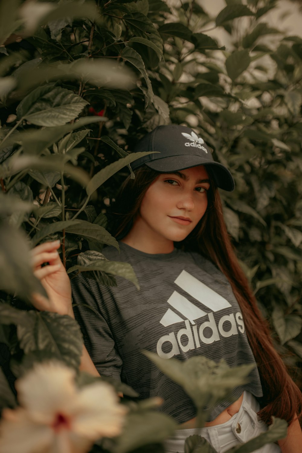 Foto de mujer con camiseta gris adidas y gorra apoyada en plantas verdes –  Imagen gratuita Vestir en Unsplash
