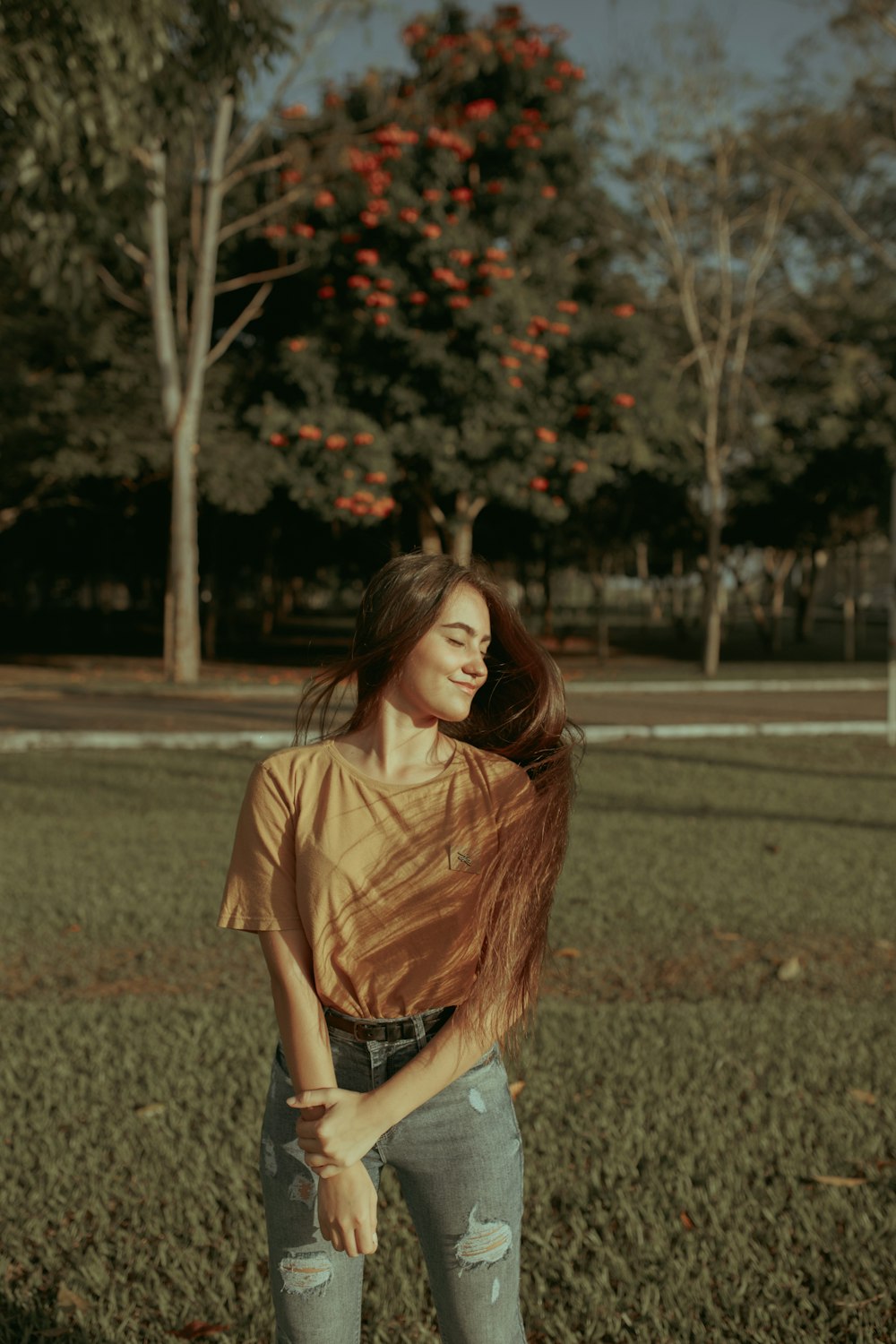 woman in orange crew-neck t-shirt and distressed blue denim jeans