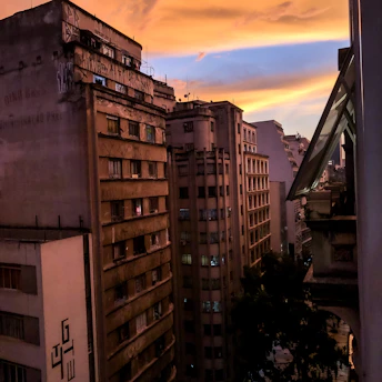 A gritty Detroit street scene at dusk, with worn brick buildings and a mural celebrating blue-collar workers.