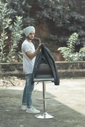 A man wearing a crisp white panjabi paired with casual jeans, walking through a city park.