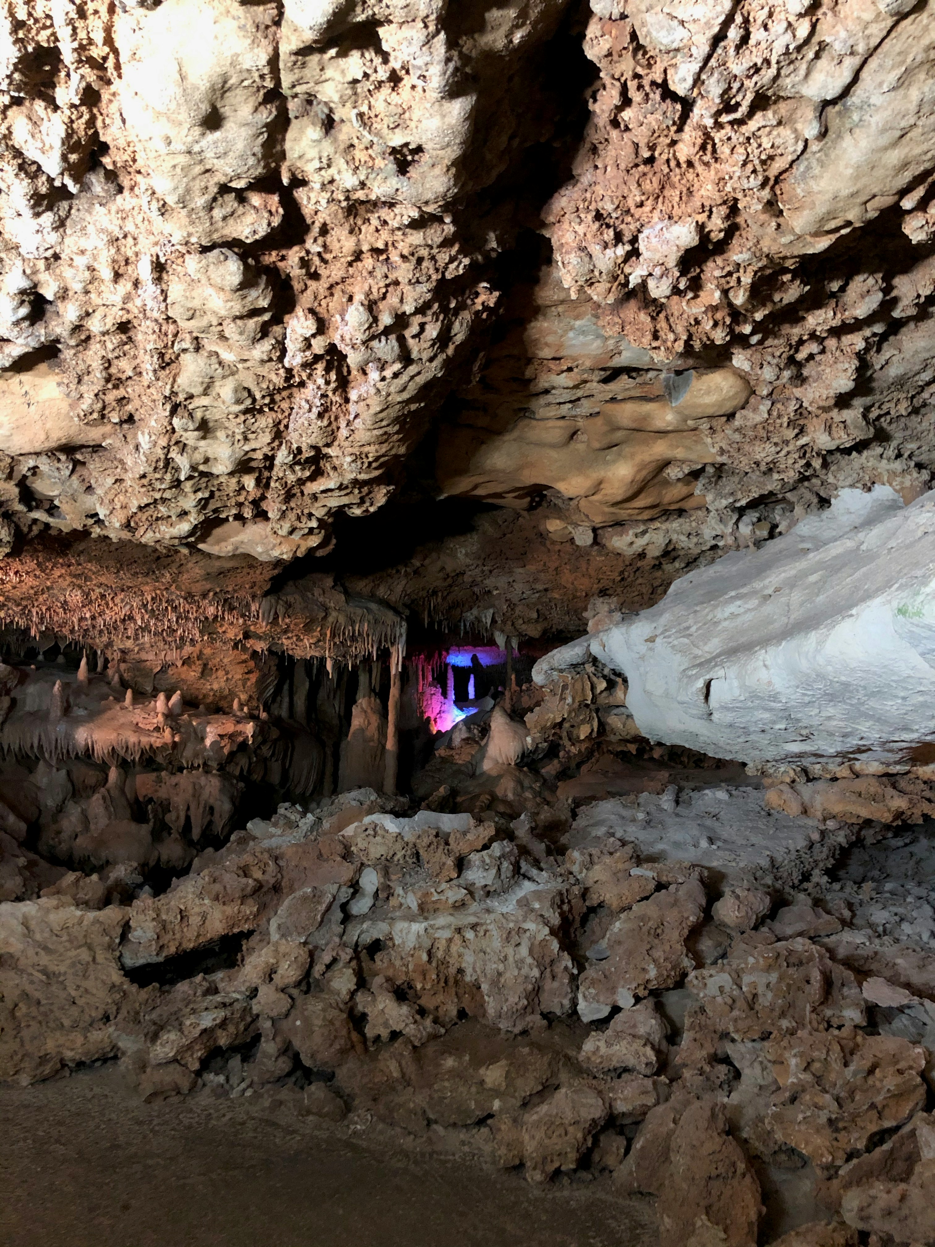 Temný interiér jeskyně s osvětlenými stalaktity a stalagmity, dramatické podzemní osvětlení, kamenné formace