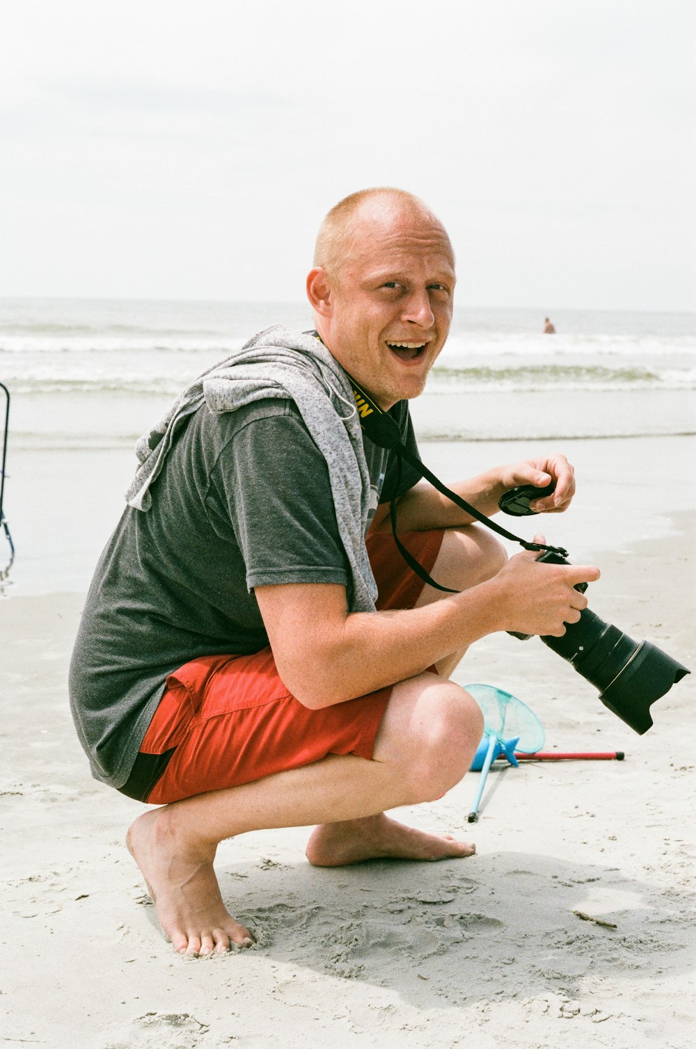 smiling man in shorts holding DSLR camera