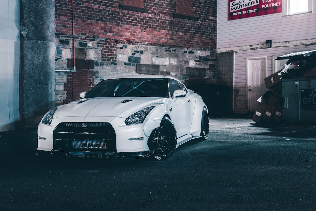 white coupe beside brick wall