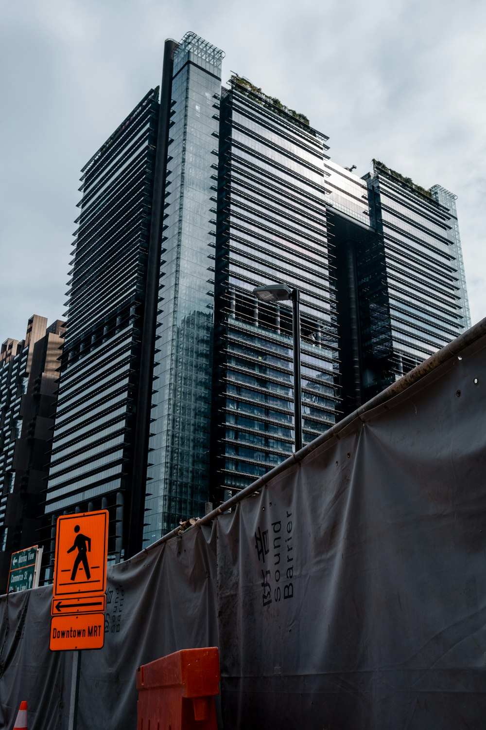 orange road sign in front of curtain wall high-rise building