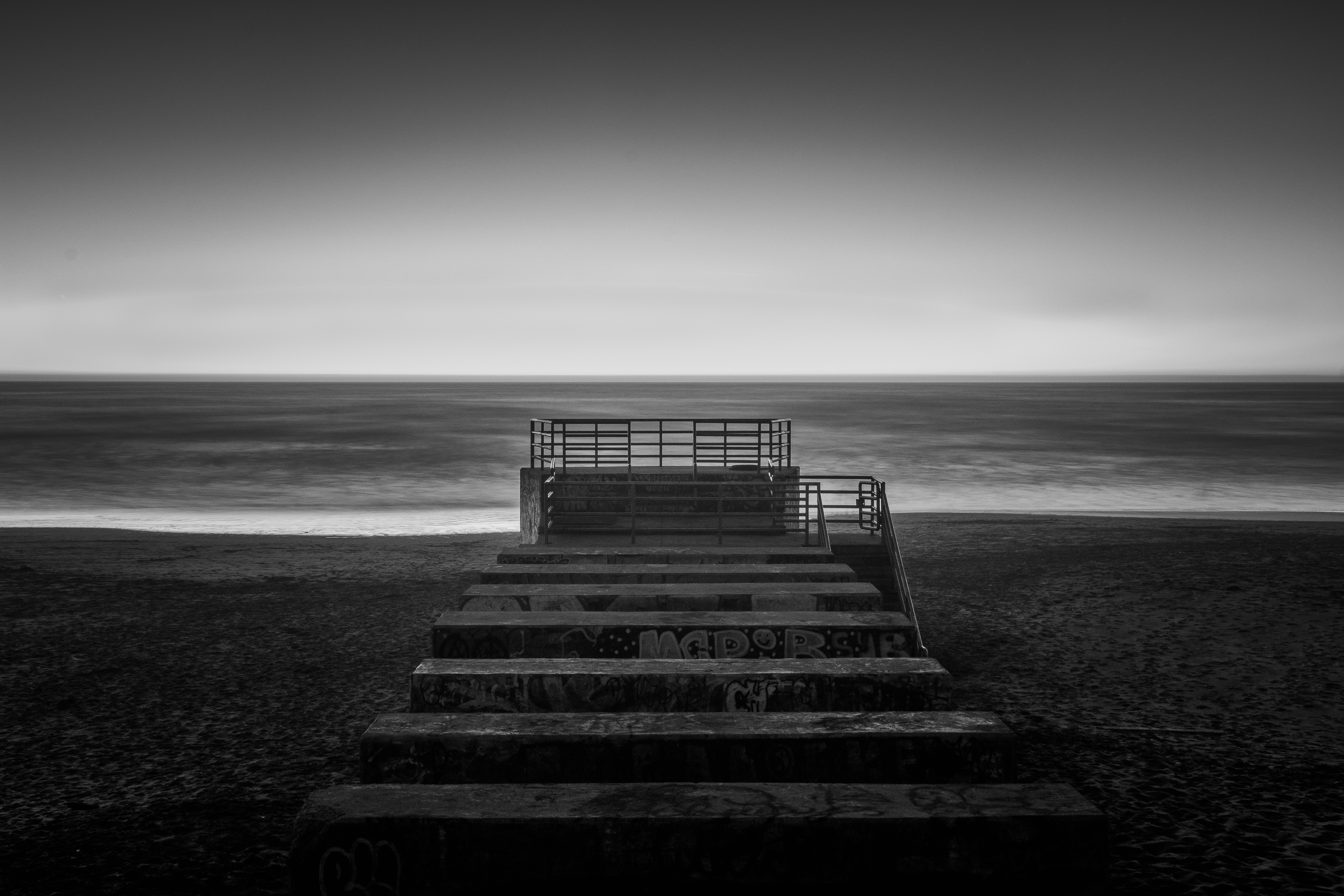 grayscale photography of concrete stair near sea