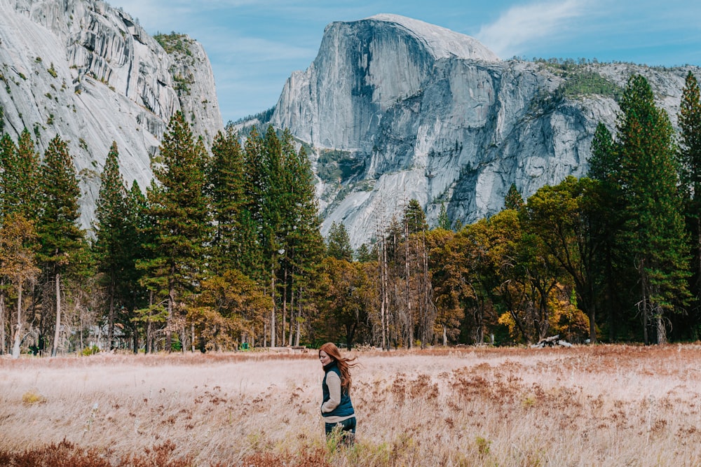 woman walking near green trees beside mountain