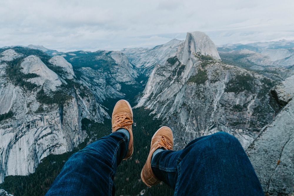 person wearing blue denim jeans and brown leather shoes