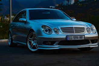 A sleek black luxury sedan parked in front of a modern mountain lodge at sunset.