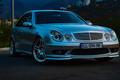 Sleek black luxury sedan parked on a quiet mountain road at dusk.