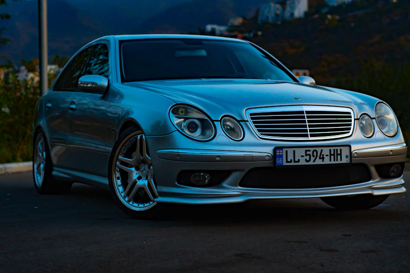 A sleek silver sedan parked by a scenic mountain road at sunset.
