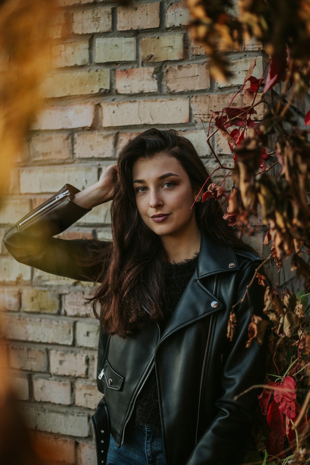 woman wearing black leather jacket leaning on wall