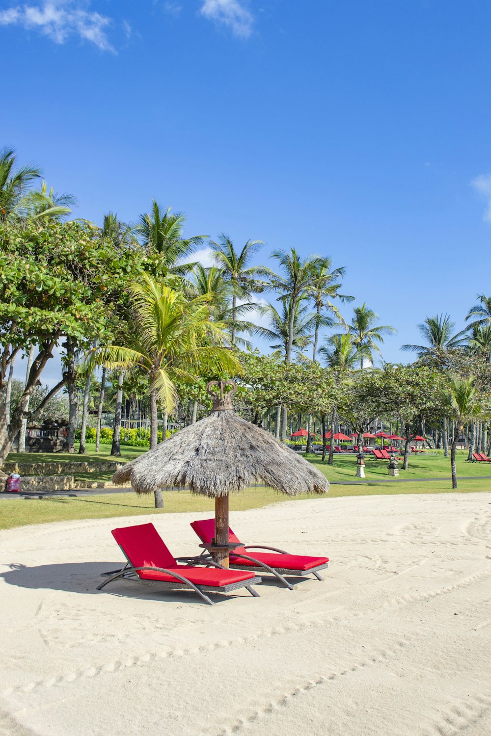 two red padded lounges on white sand during daytime