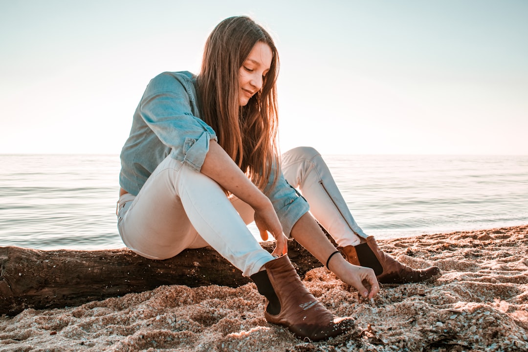 woman sitting on tree log near seashore