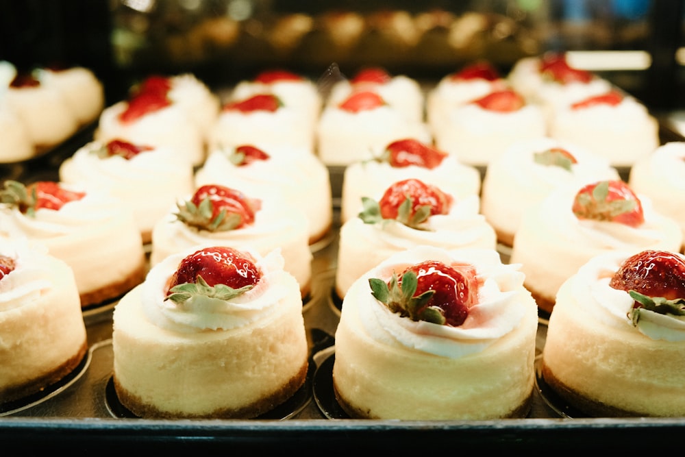a close up of a tray of cupcakes with strawberries on top