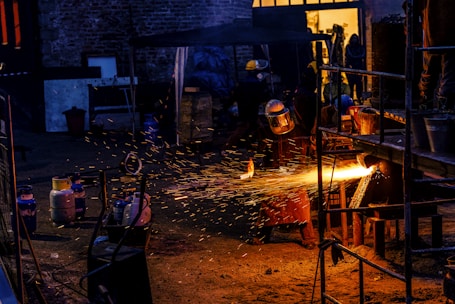 Industrial workers using oxy-fuel cutting equipment on a large metal structure.
