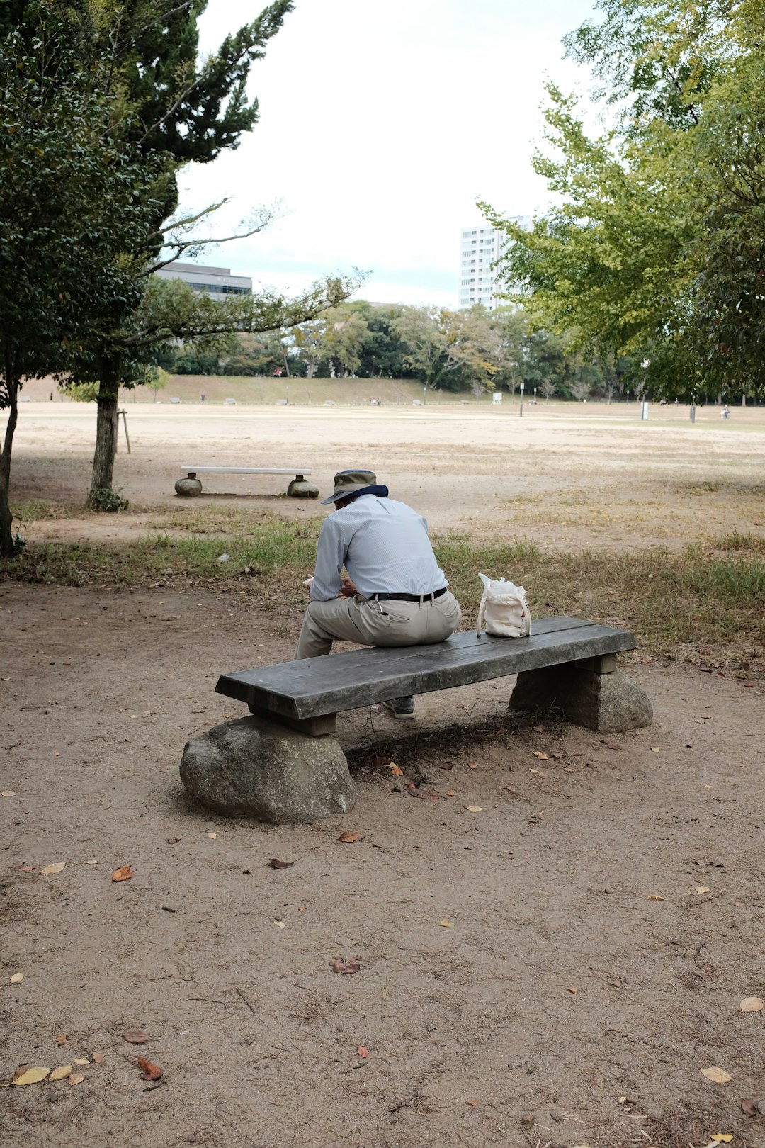 man sitting on bench near trees during day