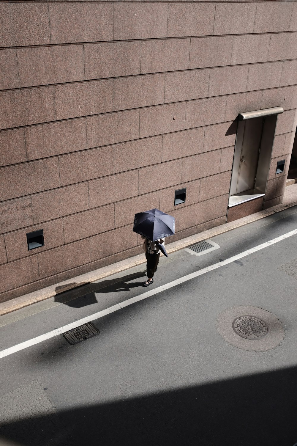Persona che cammina accanto all'edificio in cemento marrone