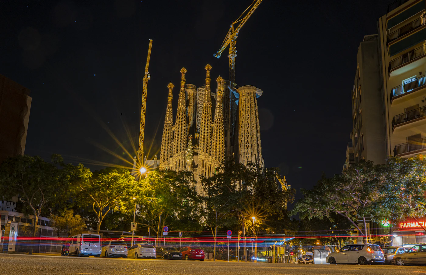 De verlichte Sagrada Família in Barcelona bij nacht met verkeer op de voorgrond
