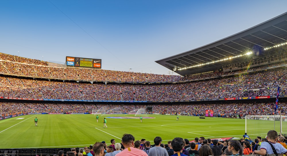 people watching soccer game inside stadium during day