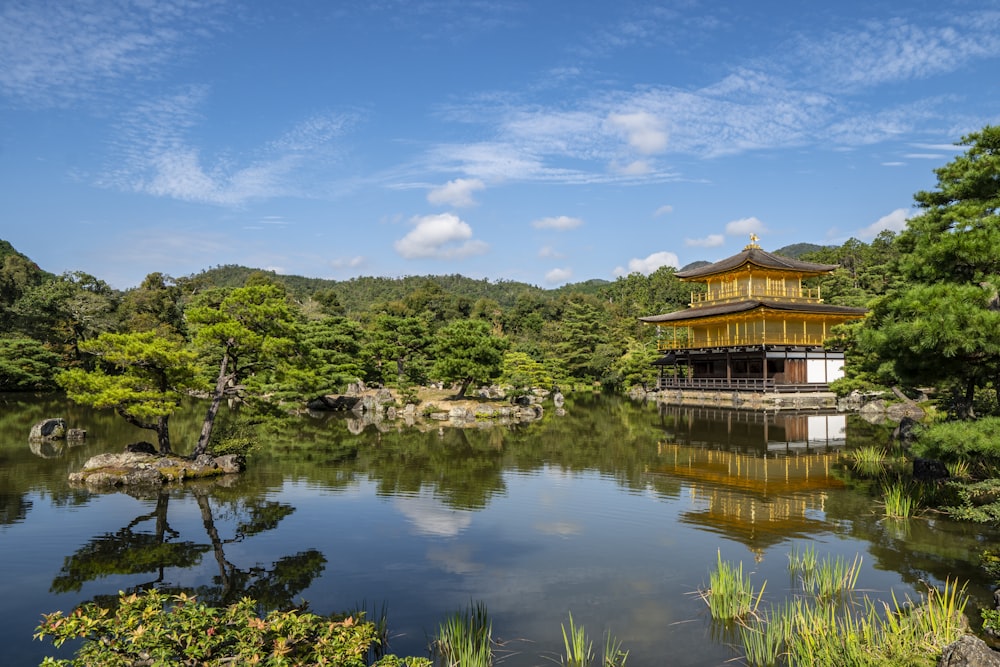 yellow and brown temple surrounded with trees and facing body of water