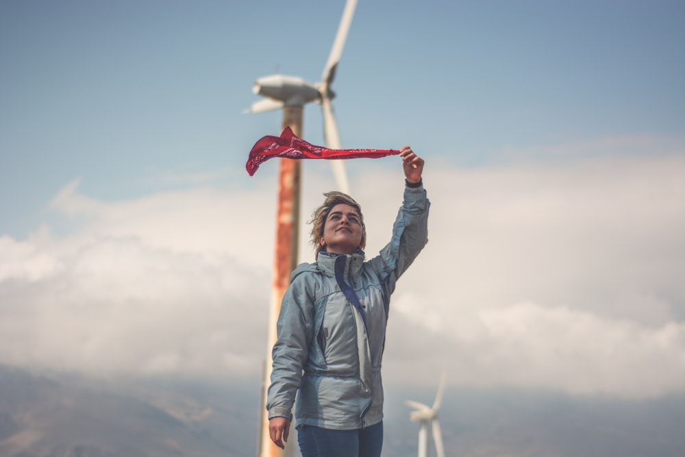 standing person wearing gray jacket near wind turbines