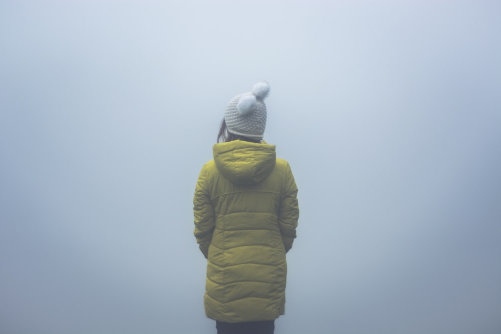 person wearing green hooded jacket standing while facing back