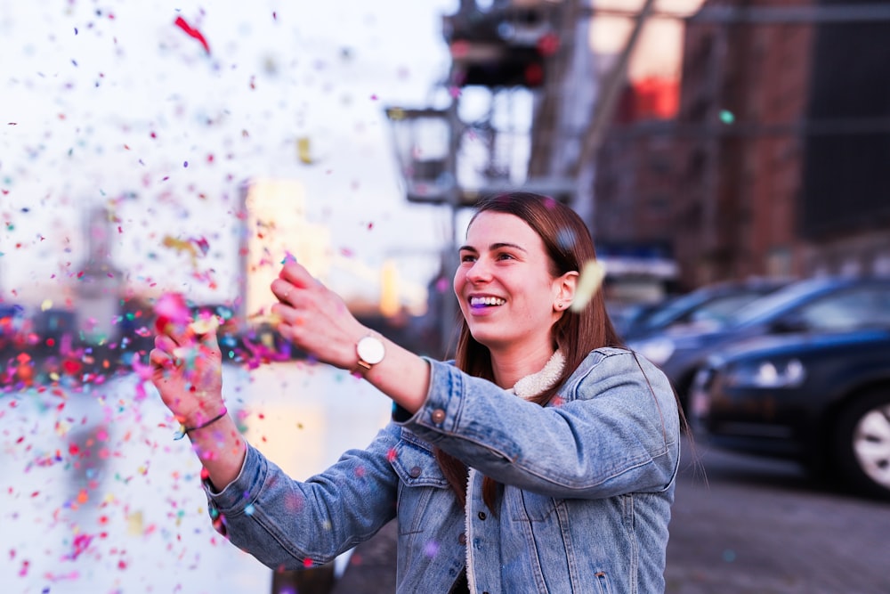 woman in blue denim jacket popping confettis