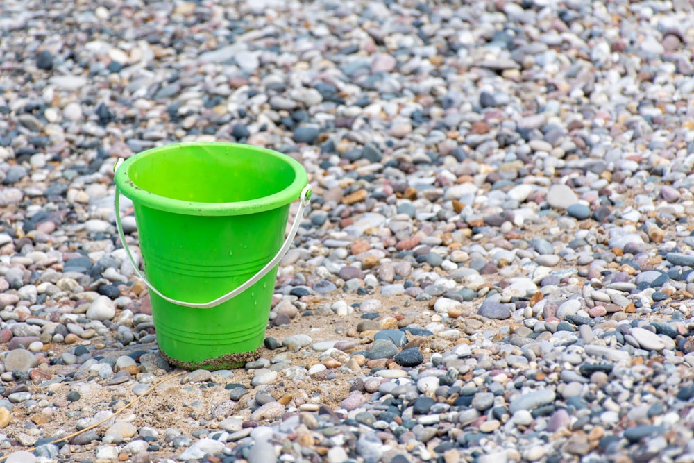 Seau en plastique vert sur pierres