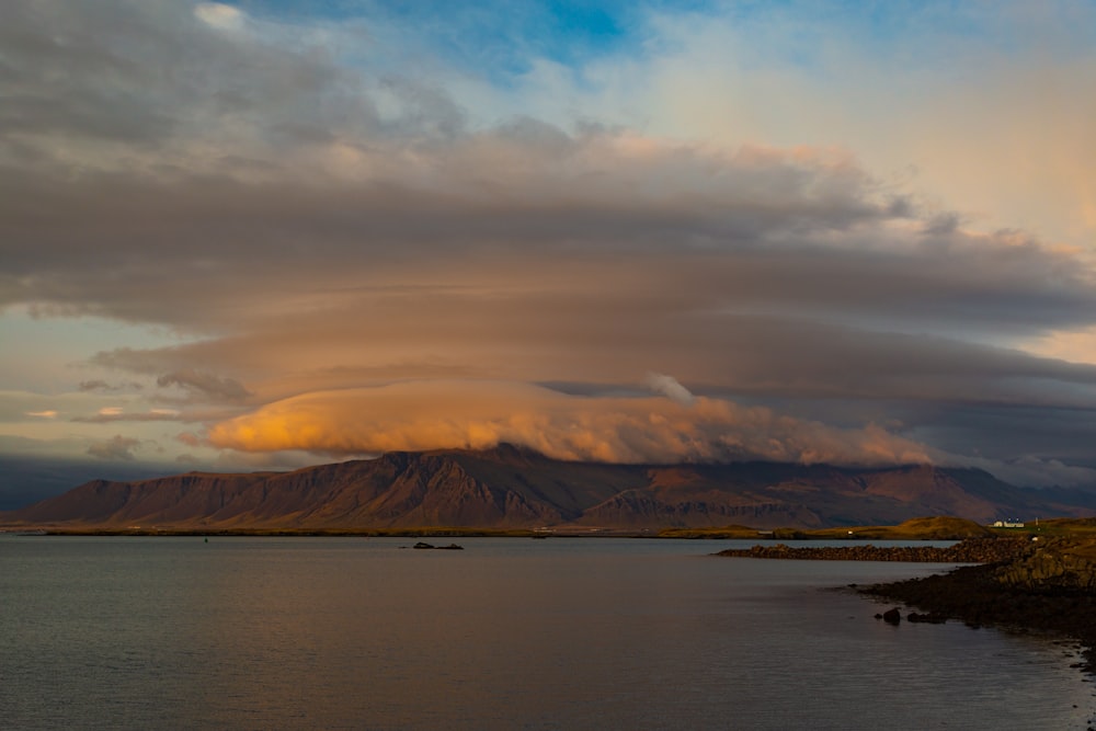 aerial photography of blue body of water viewing mountain under white and orange sky during daytime