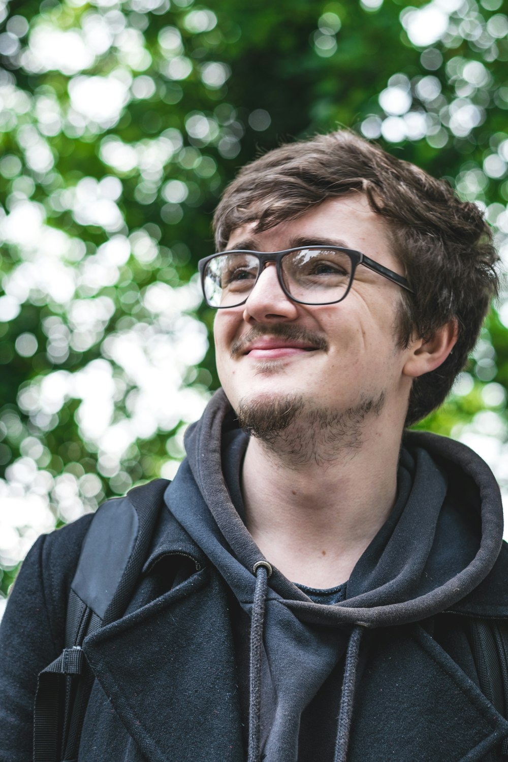 man wearing black pullover hoodie and black framed eyeglasses