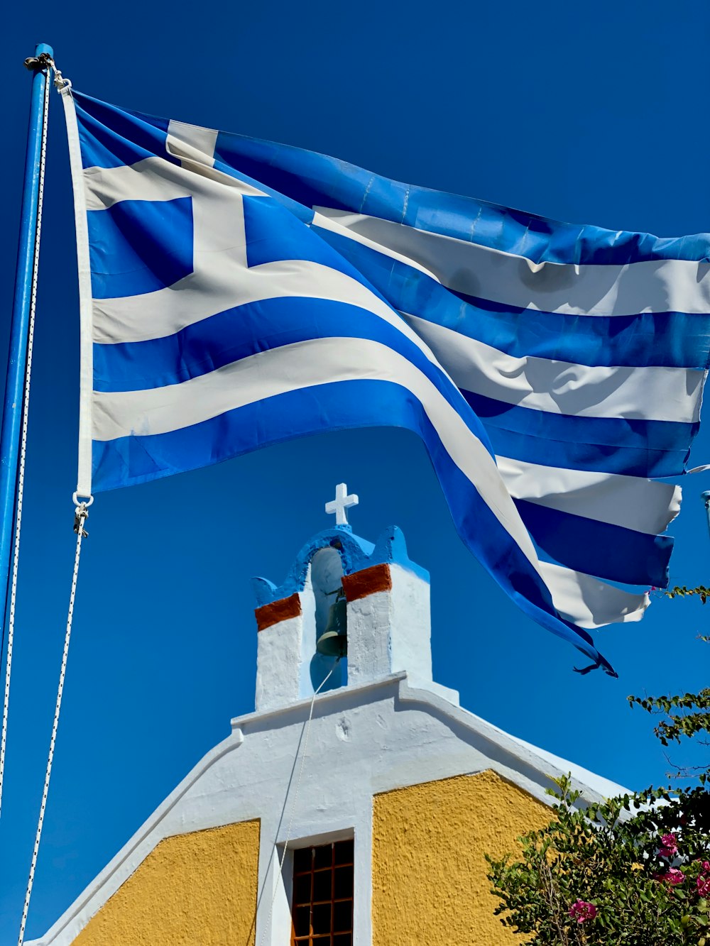 raised Greece flag near cathedral during daytime