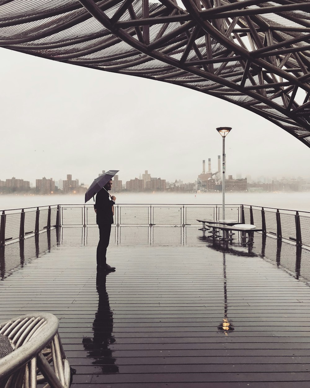 uomo in piedi sul molo dell'oceano che tiene l'ombrello