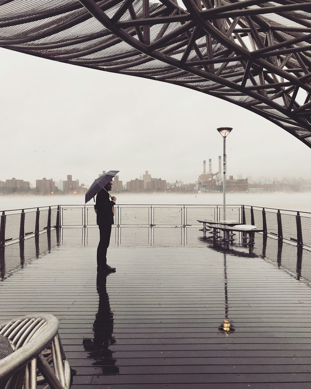 Mann, der auf dem Meeresdock steht und einen Regenschirm hält